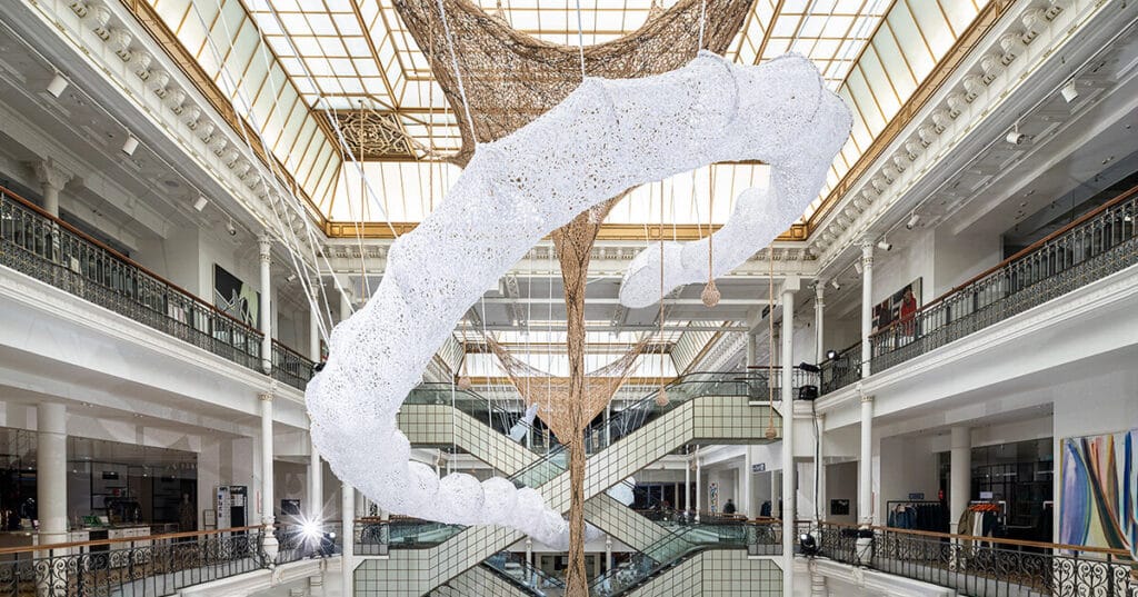 ernesto neto suspends monumental crochet serpent within le bon marché in paris