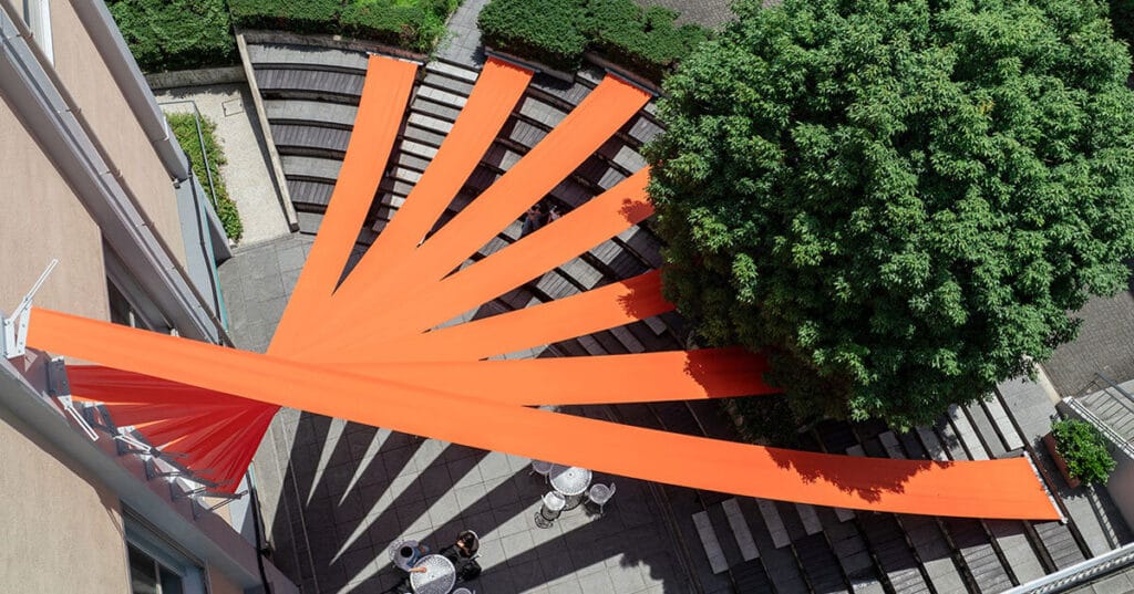 bright orange fabric panels fan out above university’s amphitheater in japan