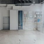 1975 men’s hair salon unfolds within transparent acrylic frame