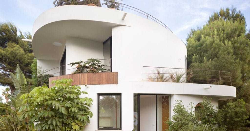 organic residence’s curved white planes emerge from lush greenery in spain