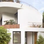 organic residence’s curved white planes emerge from lush greenery in spain